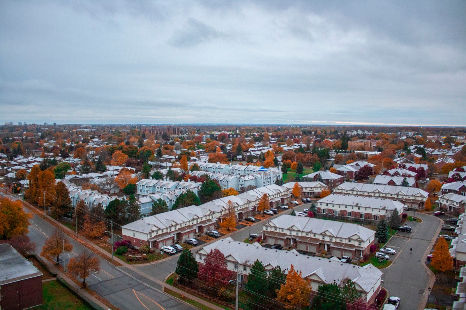 Aerial view of an Ontario suburban neighbourhood with townhouses and autumn trees under an overcast sky.